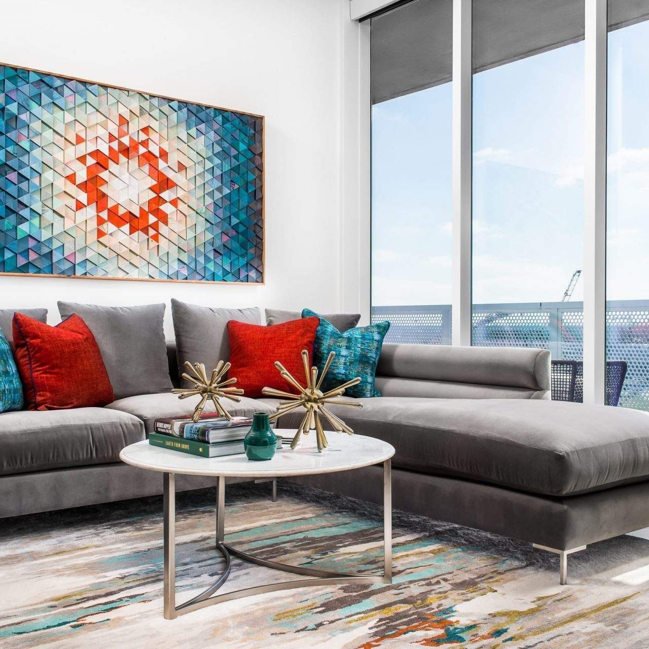 Etch Design Group in Austin, Texas - designing a condo downtown Austin for a bachelor - inviting, lively space with wallpaper, pops of color, warm wood tones, and neutral furnishings for a cohesive design - bright wall art over a gray couch.